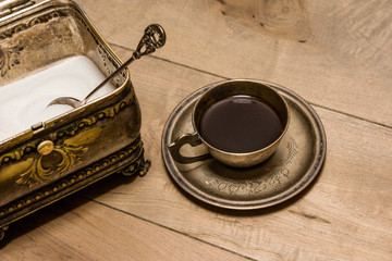 Cup of coffee and sugar bowl on oak table