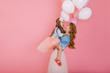 © Look! - Portrait of happy little birthday girl with long hair holding balloons and hugging her young stylish mom after event. Charming excited mother posing with daughter at party isolated on pink background