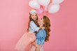 © Look! - Fascinating curly mother and beautiful little daughter in the same attire posing together after birthday party. Portrait of charming girl in lush skirt hugs her elder sister with love and smile