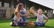 © Kitreel - Portrait of a happy young mother farmer is showing fresh biologic  just harvested carrots to her small daughters on a background of a countryside farm.