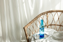 Rattan Chair With Blue Bottle Decorations At The Daylight
