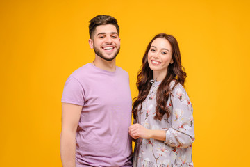 Wall Mural - Photo of young couple man and woman smiling isolated over yellow background