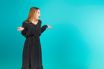 Wall Mural - Surprise young woman looking at copy space isolated over turquoise blue background