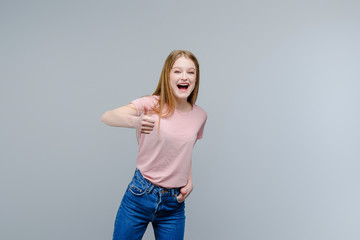 Wall Mural - Young attractive girl showing thumbs up isolated over gray background