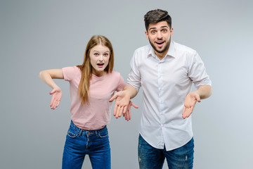 Wall Mural - Young guy and girl pointing down isolated over gray background