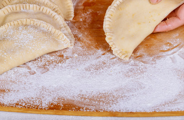 Clouse up raw pasties and flour on the table