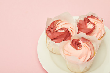 plate with sweet tasty cupcakes on pink surface