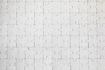 White jigsaw puzzle. White puzzle pieces on color background. Unfinished white jigsaw puzzle pieces on color background.