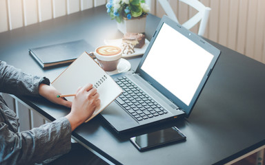 Closeup young asian woman working with laptop and writing on note