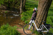 Ausflug mit Elektro Fahrrad, Radfahrerin mach Pause an schöner Bachlandschaft