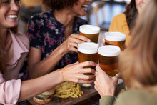 Close Up Of Four Young Female Friends Meeting For Drinks And Food Making A Toast In Restaurant