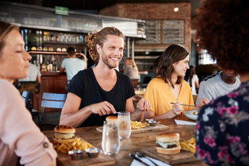 Group Of Young Friends Meeting For Drinks And Food In Restaurant