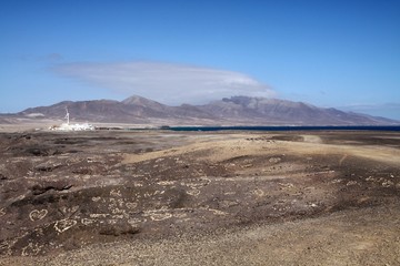  View on small white village, mountain range and spot of blue ocean over endless barren land, Fuerteventura, Canary Islands