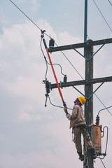 The power lineman use clamp stick (insulated tool) to closing a transformer on energized high-voltage electric power lines. The power lineman must be trained because it is a risky job.