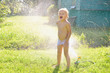 © jordano - Child playing with garden sprinkler under trees