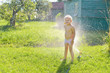 © jordano - Child playing with garden sprinkler under trees
