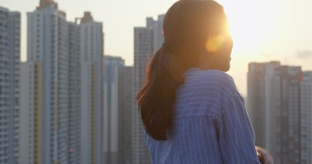 Poster - Woman look at the city with skyscraper under sunlight flare