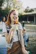 © Maskot - Cheerful woman having drink while standing at lawn in music festival