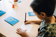 © Maskot - High angle view of schoolboy practicing alphabets at table in classroom