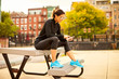 © Cavan Images - An athletic woman texting while sitting on a picnic table in a park.