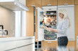 © Westend61 - Content mature woman standing in kitchen at smart home checking fridge with digital tablet