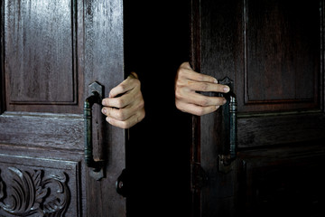 Wall Mural - Hands open the wooden door from the inside of the dark room.