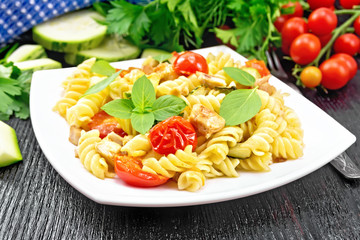 Wall Mural - Fusilli with chicken and tomatoes in plate on black wooden board