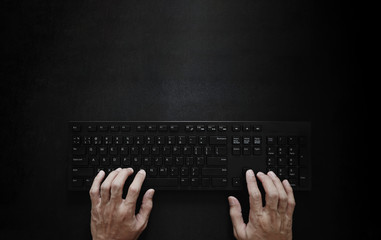 top view, hand typing computer keyboard on black background
