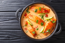 Tender Salmon Fillet In Spicy Thai Coconut Curry With Lime And Herbs Close-up In A Pan. Horizontal Top View