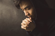 © christianchan - Praying Man Against Dark Background With Copy Space