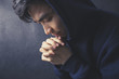 © christianchan - Praying Man Against Dark Background With Copy Space