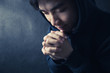 © christianchan - Praying Man Against Dark Background With Copy Space