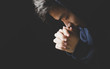 © christianchan - Praying Man Against Dark Background With Copy Space