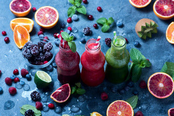 Wall Mural - Colorful smoothies in bottles with berries and citrus fruits, healthy vitamin drink