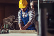 © zorandim75 - Carpenter measuring on a wooden bar standing at a table in a workshop