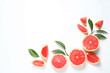 Frame made of grapefruits and leaves on white background, top view with space for text. Citrus fruits