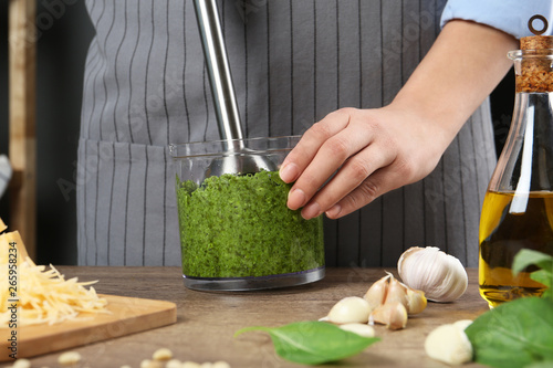 Fotografía Woman blending pesto sauce in bowl at table, closeup