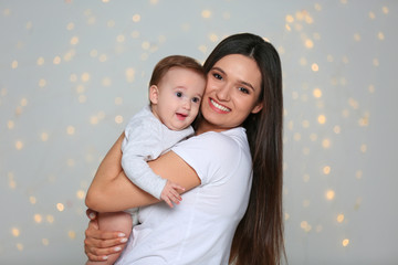 Canvas Print - Portrait of young mother and her adorable baby against defocused lights