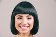 Young woman with black hair posing on camera. Cheerful nice model smile. Black bob haircut. Isolated on light background.