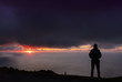 © poliki - backlit man with orange sun in the background, after bad weather with dark clouds