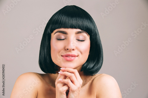 Young Woman With Black Hair Posing On Camera Dreamy Nice Model Keep Eyes Closed And Hands Together Smile Calm And Peaceful Isolated On Light Background Buy This Stock Photo And Explore