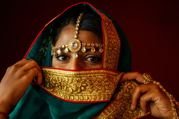 Woman lighting diyas with nuth nath nose piercing and the golden teak with traditionak fashion sari