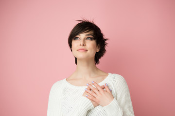 Young pretty woman  smiling and looking up to the top left corner with hands on chest and grateful gesture on face. Happy smiling woman feels grateful