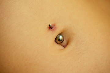 Belly piercing in the navel close up