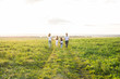 © satura_ - Family, summer and holiday concept - Group of women and girls going away in green field