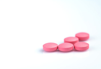 Wall Mural - Round pink tablets pill on white background. Vitamins and minerals plus folic acid vitamin E and zinc in drug bottle on gradient background. Pink tablets pills for during and after pregnancy woman.