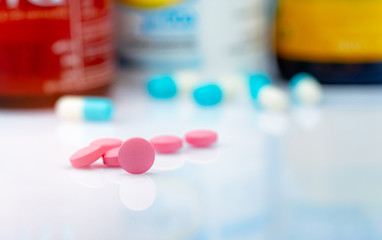 Poster - Round pink tablets pill on blurred background of drug bottle. Painkiller medicine. Drug use for treatment migraine headache. Pharmacy products. Pharmaceutical industry. Drug use in daily life.