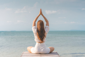 Back of views woman practice yoga lotus pose to meditation summer vacation on pier with sae and beach feeling so happiness and cheerful,Travel in tropical beach in Thailand,vacations and relaxation