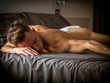 © theartofphoto - Shirtless sexy male model lying alone on his bed in his bedroom, looking at camera with a seductive attitude