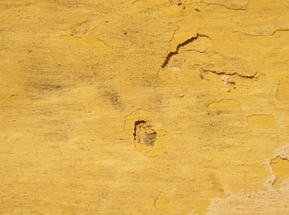 Wall Mural - a rough old plaster wall with cracks and dirt with layers of yellow paint